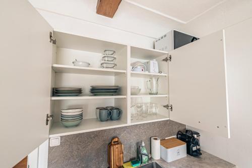 a kitchen with white cabinets and plates on shelves at SIEGLGUT in Altaussee