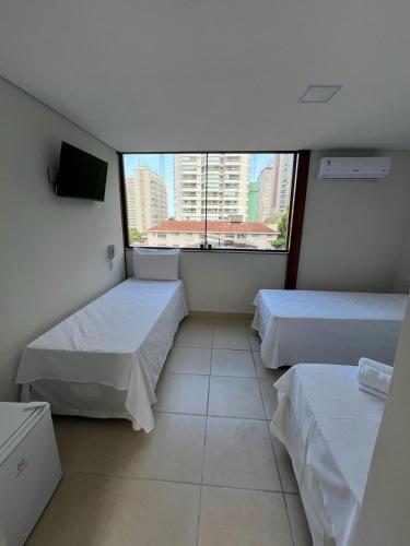 a room with two beds and a large window at Hotel Santa Catarina in Santos