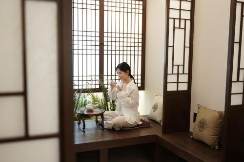 a woman in white sitting on a table in a room at D A L Premium Capsule Hotel in Seoul