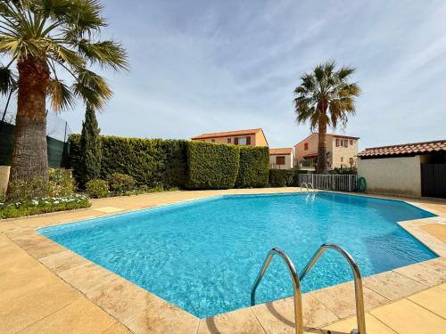 une piscine avec des palmiers et une maison dans l'établissement Splendide - Piscine - Plage 500m, à Carqueiranne