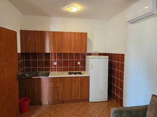 a kitchen with wooden cabinets and a white refrigerator at Vila Marina in Buljarica