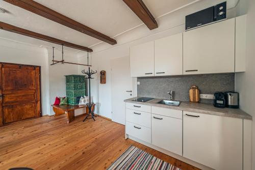 a kitchen with white cabinets and a wooden floor at SIEGLGUT in Altaussee