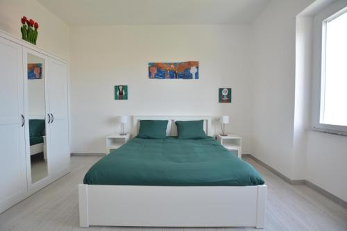 a white bedroom with a large bed with green sheets at 7th Floor - Donoratico in Cagliari