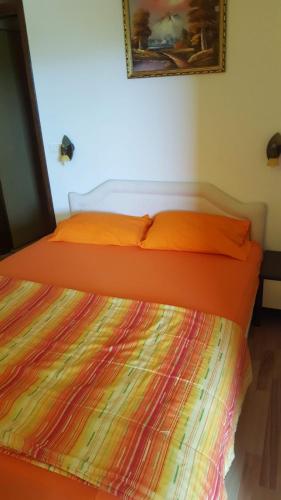 a bed with an orange comforter in a room at Vila Marina in Buljarica