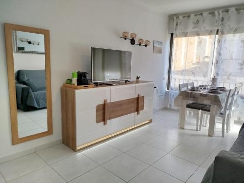 a living room with a tv on a cabinet and a table at Bonito Apartamento en el centro de Roses in Roses
