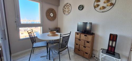 une salle à manger avec une petite table et une télévision dans l'établissement GRAND STUDIO VUE PANORAMIQUE SUR LE PORT, PARKING PRIVE, au Cap d'Agde