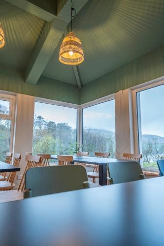 a large room with tables and chairs and windows at Otter Hostel Connemara in Leenaun