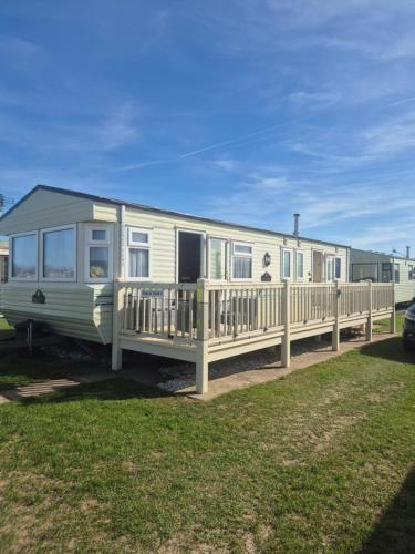 a mobile home with a porch and a fence at Mark and Teresa's 8 berth caravan on Coral Beach Ingoldmels in Ingoldmells