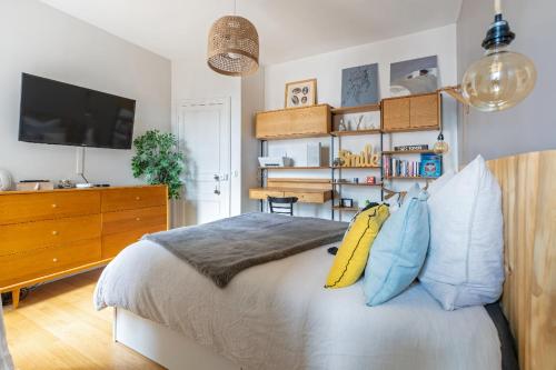 - une chambre avec un lit doté d'oreillers et une télévision dans l'établissement Cozy Pineapple - proche du 17 eme, à Asnières-sur-Seine