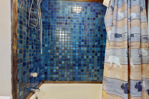 a bathroom with a blue tiled shower with a shower curtain at Hyak Duplex Cabin in Snoqualmie Pass