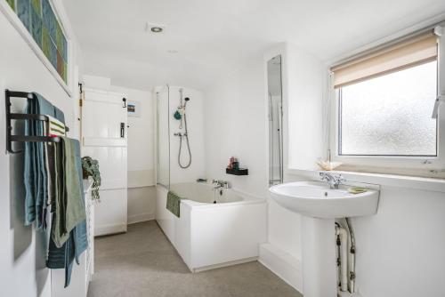 a white bathroom with a sink and a bath tub at Meads Cottage in Charmouth