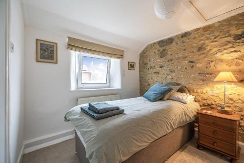 a bedroom with a bed and a stone wall at Meads Cottage in Charmouth