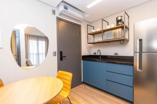 a kitchen with a table and a sink and a mirror at Vibe Curitiba by Housi, próximo à Ligga Arena e Praça do Japão in Curitiba