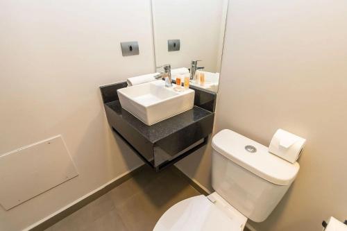 a bathroom with a white toilet and a sink at Vibe Curitiba by Housi, próximo à Ligga Arena e Praça do Japão in Curitiba