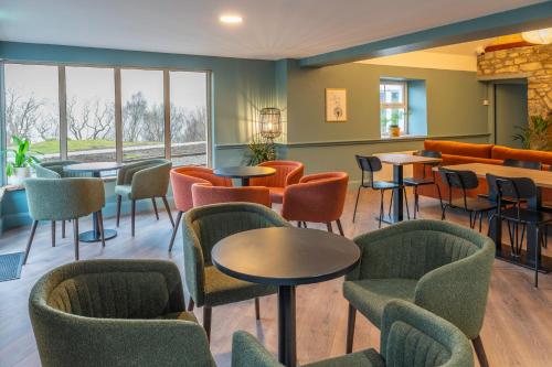 a waiting room with tables and chairs and windows at Otter Hostel Connemara in Leenaun