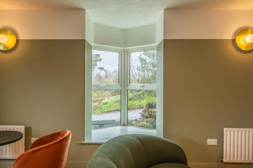 a living room with a window and two chairs at Otter Hostel Connemara in Leenaun