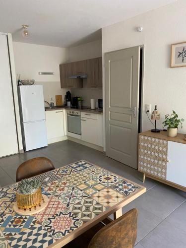 Il comprend une cuisine équipée d'une table et d'un réfrigérateur. dans l'établissement Charmant appart. 3-4 pers., à Saleilles