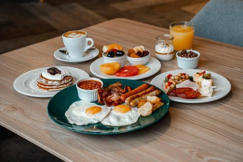 a table topped with plates of breakfast foods and coffee at OREA Hotel Pyramida Praha in Prague