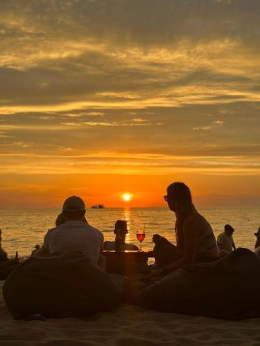 a group of people sitting on the beach watching the sunset at Sunset Beach Resort and Spa in Phu Quoc