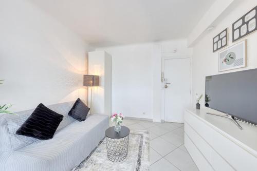 a white living room with a white couch and a flat screen tv at Hyper Centre Villejuif à côté du M7 proche de Paris in Villejuif