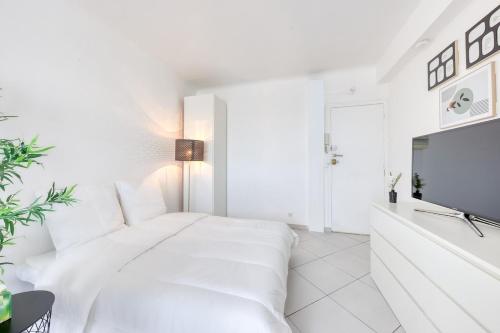 a white bedroom with a large white bed and a tv at Hyper Centre Villejuif à côté du M7 proche de Paris in Villejuif
