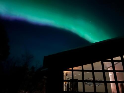 an image of the aurora borealis over a building at Discover Iceland Private Lodges Two Houses in Blaskogabyggd