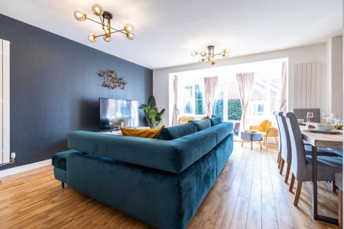 a living room with a blue couch and a dining room at Modern and Spacious Home From Home 1 mile from M1 - with Netflix, Prime Video, PS5, free parking, superfast WiFi, BBQ - Sleeps 11 - By Brightleap Apartments in Milton Keynes