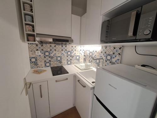 une petite cuisine avec des armoires blanches et un micro-ondes dans l'établissement Charmant T2 avec Terrasse à Saint Aygulf - Idéal pour 3 personnes, à Fréjus
