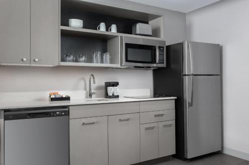 a kitchen with white cabinets and a stainless steel refrigerator at Homewood Suites By Hilton Newport Cincinnati in Newport