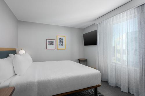a white bedroom with a bed and a window at Homewood Suites By Hilton Newport Cincinnati in Newport