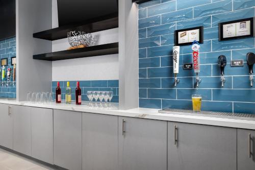 a bar with a blue tile wall with wine glasses at Homewood Suites By Hilton Newport Cincinnati in Newport