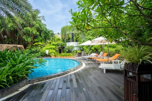 a swimming pool in a garden with a wooden deck at Sunset Beach Resort and Spa in Phu Quoc