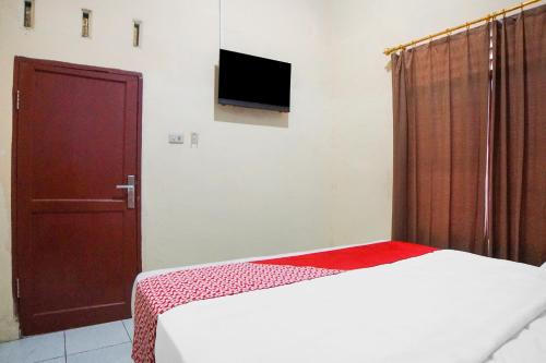 a bedroom with a bed and a door and a television at Hotel O Sky Residence Cengkeh in Medan