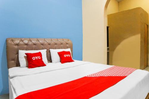 a large bed with two red pillows on it at Hotel O Sky Residence Cengkeh in Medan