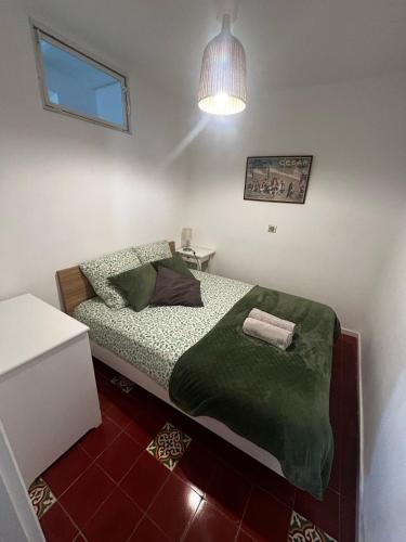 - une petite chambre avec un lit et une couverture verte dans l'établissement Cabanon de Malmousque, à Marseille