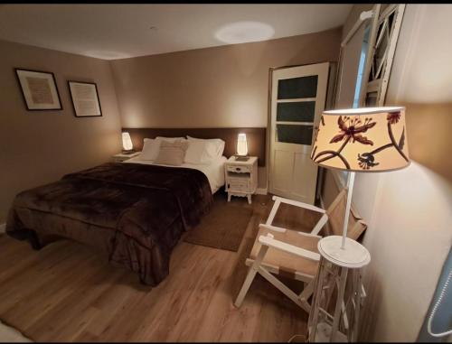 a bedroom with a bed and a lamp and a chair at Casa do Ti Messias in Almeida