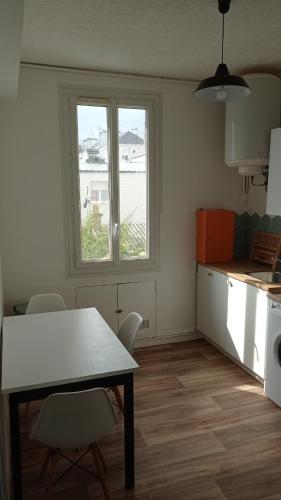une cuisine avec une table et des chaises et une fenêtre dans l'établissement Appartement rénové hypercentre plage à 5 minutes à pied, à Saint-Nazaire