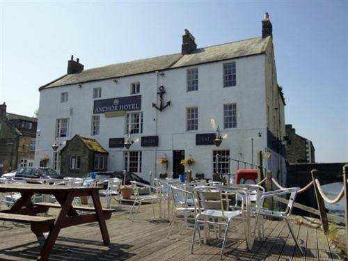 a building with chairs and a table in front of it at Anchor Hotel Haydon Bridge in Hexham