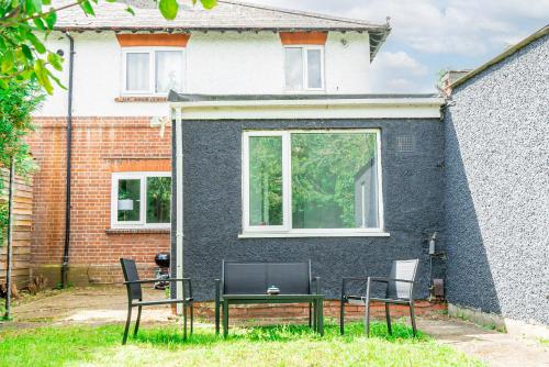two chairs and a table in front of a house at Charming 2-Bedroom Flat with a Garden and Free Parking at Abingdon in Oxford
