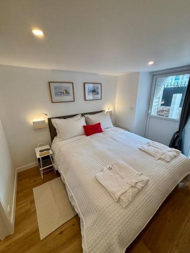 - une chambre avec un grand lit blanc et un oreiller rouge dans l'établissement Les Thermes- Apartment, à Saint-Malo