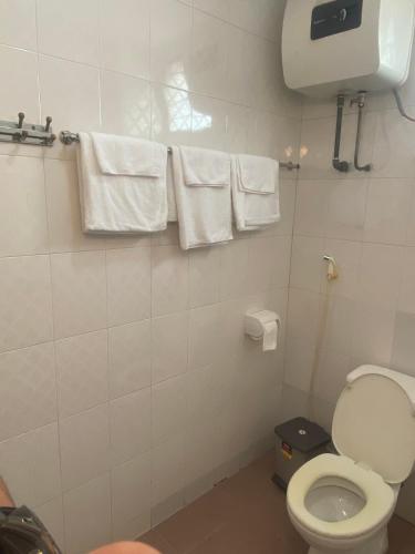 a bathroom with a toilet and towels on a wall at Kim's Family Hotel in Ha Long
