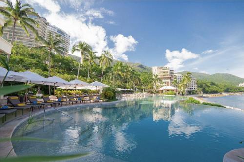 a pool at a resort with chairs and umbrellas at Garza Blanca Condo in Puerto Vallarta