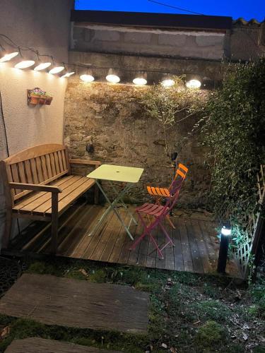 une terrasse en bois avec un banc, une table et des chaises dans l'établissement Logement entier - Le pigeonnier de la plume, à Nantes