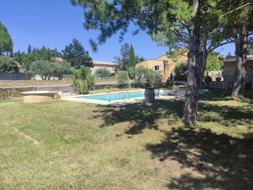 - une piscine dans une cour avec un arbre dans l'établissement Maison d'hôtes avec piscine en juillet et août, à Châteauneuf-du-Pape