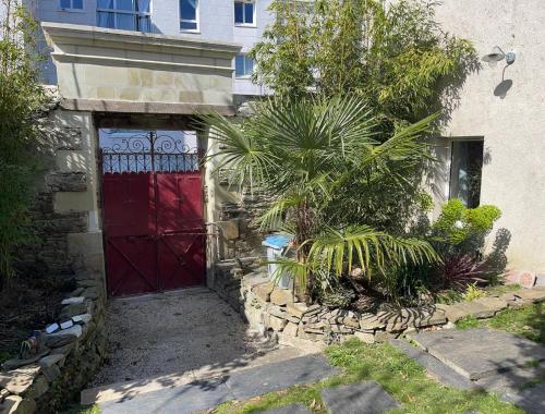 a red door of a house with a palm tree at Maison indépendante cosy avec terrasse privée - La Laiterie in Nantes