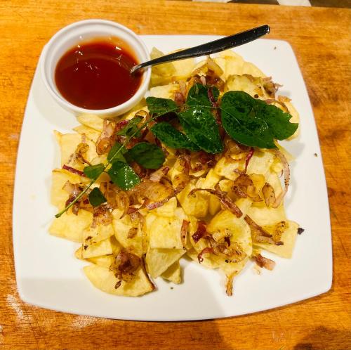 a plate of food with chips and a dipping sauce at Wild Blossom Sigiriya in Sigiriya