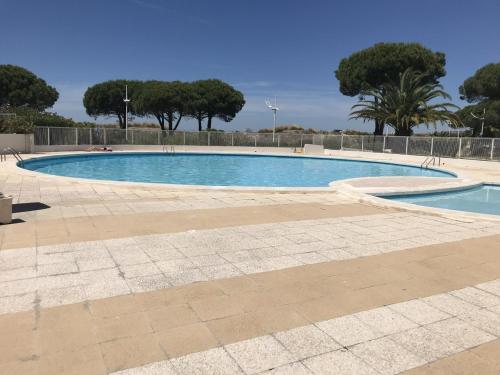 une grande piscine avec des arbres en arrière-plan dans l'établissement Studio cabine L Escale Plage, au Grau-du-Roi