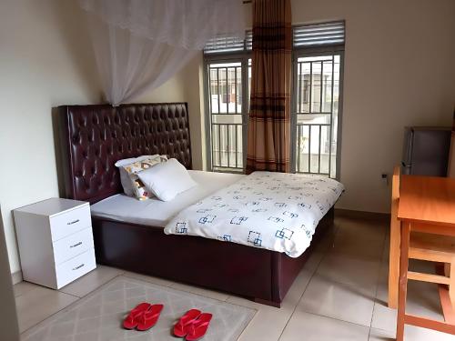 a bedroom with a bed with red slippers on the floor at Maison De Omashi in Kigali