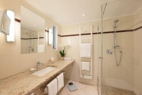 a white bathroom with a sink and a shower at Kastens Hotel Luisenhof in Hannover