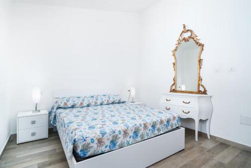 a bedroom with a bed and a dresser and a mirror at CASE ORCHIDEA - ROSA BLU in La Caletta